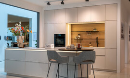 Ervaar de verfijning van de greeploze, lichte designkeuken met een modern keukeneiland en ronde eetbar. Deze keuken straalt stijl en elegantie uit, dankzij de minimalistische frontdeuren en praktische indeling. Zuordnung: Stil Moderne keukens, Planungsart Keuken met keukeneiland