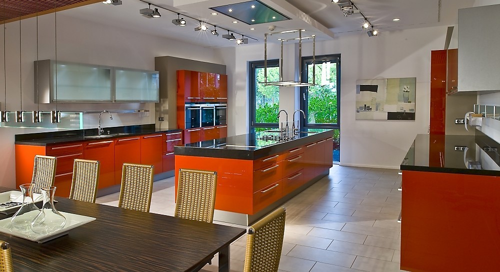 Open keuken met hoogglans aanrechtbladen en fronten, oranjerood. Tegen de muur hangkasten met glazen deurtjes. Zuordnung: Stil Moderne keukens, Planungsart Keuken met keukeneiland