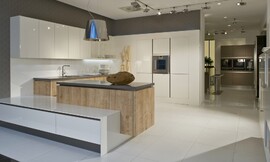 Een aantal kalme witte meubels worden hier gecombineerd met een prachtig eiken houten keukeneiland. Op de witte onderkast ontstaat zitgelegenheid. De hoge kast is in de wand verwerkt, waardoor deze minder opvalt. Zuordnung: Stil Landelijke keukens, Planungsart U-vormige keuken