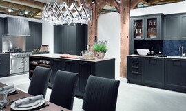 Deze open keuken heeft matzwarte kader fronten met grepen en een dun aanrechtblad. Passend is ook de bovenkast met glazen deurtjes. Hier uitgevoerd met een luxe fornuis. Zuordnung: Stil Landelijke keukens, Planungsart U-vormige keuken