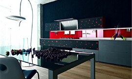 Design keuken van gerecycled glas. Greeploze grijze en zwarte fronten met rode stippen, felrode keukenachterwand. De afzuigkap zit in de bovenkast ingebouwd en kan open- en dichtgeklapt worden. Deze keuken laat zien wat fronten met creatieve opdruk voor het totaalbeeld kunnen betekenen. Zuordnung: Stil Moderne keukens, Planungsart L-vormige keuken