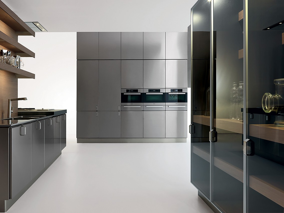 Deze moderne keuken voldoet aan alle wensen. Rechts een hoogkast met donker glas, achter een hoogkast met solide metallic fronten met subtiele grepen en ingebouwde apparatuur en links een werkblad en fornuis Zuordnung: Stil Design-keukens, Planungsart keukenblok