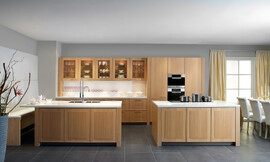 Moderne landelijke keuken met gebeitst eiken fineer "tonnato" en nette witte aanrechtbladen. Het grootste keukenblok is tegen de wand geplaatst en biedt in de lades veel bergruimte. Daarboven hangen kastjes met glazen deuren, zo kan het mooie servies ook als decoratie-object worden gebruikt. Op de legplanken in de nis is er plaats voor de mooiste glazen en andere accessoires. Rechts zijn de hoge apparatuurkasten opgenomen. De keuken beschikt verder nog over twee eilanden. Op het ene keukeneiland is de dubbele spoelbak met praktische handdouche opgenomen. Het aanrechtblad steekt hier iets uit, zodat er door de daar geplaatste bank een fraaie zitgelegenheid is ontstaan. Op het andere eiland kan er gekookt worden. Zuordnung: Stil Landelijke keukens, Planungsart L-vormige keuken