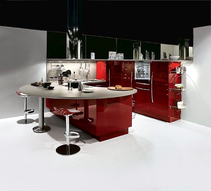 U-keuken met een combinatie van een rond aanrechtblad en bar. Zitgelegenheid op design barkrukken. Open en communicatief keukenconcept. Contrast tussen hoogglans rood en lichtgrijs werkblad. Speels keukenontwerp dat vanuit een hoek gedacht is. Zuordnung: Stil Design-keukens, Planungsart U-vormige keuken