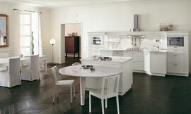 Klassieke, open keuken met zithoek aan kookeiland. Symmetrisch keukenblok met schouw (afzuigkap). Tint: wit in contrast met een prachtige donkere vloer. Links staat ook nog een grotere eetkamertafel. Zuordnung: Stil Klassieke keukens, Planungsart Keuken met keukeneiland