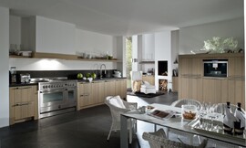 Landelijke keuken met modern accent. Hier ziet u wat een groot fornuis, typisch voor landelijke keukens, voor de keuken betekent. Hier is de afzuigkap onopvallend verwerkt in een schouw. De kasten hebben relatief brede wangen en een stenen aanrechtblad. Zuordnung: Stil Landelijke keukens, Planungsart L-vormige keuken