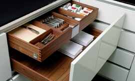 Voorbeeld van een houten bestek- en kruidenlade binnen een grotere lade. Hier uitgevoerd met hoogglans wit front. Deze combinatie biedt perfecte opslagruimte voor besteksets, kruiden en tafellakens. Zuordnung: Stil Moderne keukens, Planungsart Keuken met keukeneiland