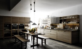 Designkeuken bestaande uit twee keukenblokken met landelijke accenten: houttinten, brede grepen, houten rekken/kasten en in het midden van de keuken een traditionele houten tafel met banken. Op het ene keukenblok, waarin zich ook de spoelbak en het fornuis bevinden, zijn half open kasten geplaatst die ideaal zijn voor het opbergen van het serviesgoed of decoratieve accessoires. Het andere keukenblok bestaat uit hoge kasten die voor een deel open zijn en daardoor aan stellingskasten doen denken. In het midden van de hoge kasten is op praktische werkhoogte de roestvrijstalen apparatuur naast elkaar aangebracht. Zuordnung: Stil Design-keukens, Planungsart Open keuken (woonkeuken)