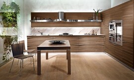 L-keuken met walnoot hout. Deze kleurtint vindt u in de keukenmeubels, tafel en stoelen. Het belangrijkste contrast is met het metaal van de afzuiging en de andere keukenapparatuur. Horizontale patronen in het hout en stijlvolle grepen maken het ontwerp af. Zuordnung: Stil Moderne keukens, Planungsart Keuken met keukeneiland