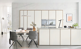 Een greeploze, tijdloze designkeuken met lichtgekleurde fronten. Deze veelzijdige opstelling biedt een zitgelegenheid en een functioneel keukeneiland. Hoogwaardige uitrusting en een praktische apothekerskast maken het compleet. Zuordnung: Stil Design-keukens, Planungsart Keuken met keukeneiland