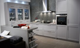U-vormige keuken met blauwgrijze cassette fronten en een opvallende achterwand met mozaïek. Op het aanrechtblad links staan opzetkasten met glazen deurtjes. Zuordnung: Stil Design-keukens, Planungsart keukenblok