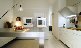 Apparatuurkasten kunnen, zoals u hier ziet, ook zwevend aangebracht worden. Deze design keuken heeft opvallend slanke fronten en aanrechtbladen, en een bijzondere driehoekige afzuigkap. Zuordnung: Stil Luxe keukens, Planungsart keukenblok