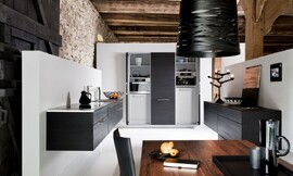 Deze moderne zwevende keuken met elegant zwart eiken fineer maakt nauwelijks meer een keuken-indruk en is daardoor prima in de woonruimte te integreren. De apparatuur is zoveel mogelijk achter deuren opgenomen, waardoor het geheel een rustige en gezellige woonindruk maakt. De sokkelvrije keuken bestaat uit drie delen: twee keukenblokken zonder bovenkasten en een driedelig blok met hoge kasten, waarachter de apparatuur verstopt is. Zuordnung: Stil Klassieke keukens, Planungsart U-vormige keuken