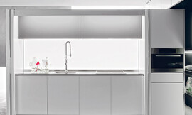 De glazen achterwand met led-verlichting maakt deze keuken tot eyecatcher. Zuordnung: Stil Design-keukens, Planungsart Keuken met zitgelegenheid