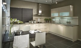 U-keuken met een aparte eettafel. Simpele fronten, gebroken wit met grepen. Wandkast met grotere panelen van donker hout. Een relatief dun granieten aanrechtblad maakt de keuken af. Zuordnung: Stil Moderne keukens, Planungsart U-vormige keuken