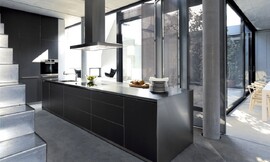 Het karakteristieke kookeiland b3 met flinterdun roestvrij stalen aanrechtblad gecombineerd met zwarte greeploze fronten. De kastenwand achteraan is in de wand ingebouwd. Zuordnung: Stil Design-keukens, Planungsart U-vormige keuken
