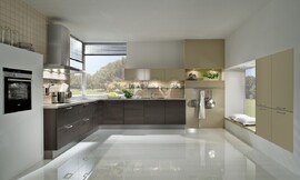 Hier ziet u de keuken reflecteren in een glanzende vloer. Eiken houtdecor fronten gecombineerd met beige (rechts). Zitgelegenheid o.a. op kussens tegen het raam. Zuordnung: Stil Moderne keukens, Planungsart L-vormige keuken