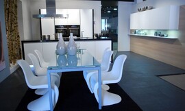 Zwart-witte keuken met greeploze fronten en blauwe verlichting in de sokkel. Hier ziet u de bijbehorende eettafel met glazen tafelblad en design stoelen. Zuordnung: Stil Design-keukens, Planungsart Keuken met zitgelegenheid