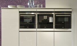 Hier ziet u een detail van de hangende hoogkast met drie apparaten en fronten met greeplijsten. Ook het paarse mozaïek is goed zichtbaar. Zuordnung: Stil Moderne keukens, Planungsart Keuken met zitgelegenheid