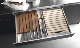 Speciale lade om uw messen beschermd en uit het zicht op te bergen. Hier uitgevoerd in een keukenkastje met metallic tinten en een rvs-aanrechtblad. Zuordnung: Stil Design-keukens, Planungsart L-vormige keuken