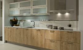 Moderne houten keuken met lichte eiken fronten gecombineerd met dunne witte aanrechtbladen en hangkasten. De deurtjes van de hangkasten zijn voorzien van matglas. Zuordnung: Stil Moderne keukens, Planungsart keukenblok